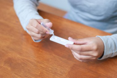 Bir kişi evde COVID-19 testi gerçekleştiriyor ve sağlık farkındalığı için kendi kendini test etmenin önemini vurguluyor.