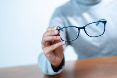 Modern bir kapalı mekan ortamında el ele tutuşan şık gözlüklerin detaylı bir görüntüsü..