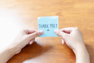 İçten bir teşekkür notu. Kapalı bir ortamda memnuniyeti simgeleyen eller tarafından tutuluyor..