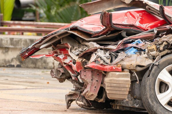 A close-up view of a damaged red car highlights the dangers of road accidents and the importance of vehicle safety.