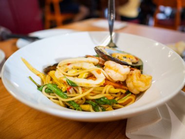 Konforlu bir restoranda karides kalamar ve sebzeli canlı bir deniz ürünleri makarnası..