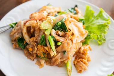 Taze deniz ürünleri ve yeşilliklerin yer aldığı canlı bir kızarmış şehriye tabağı yerel tatlar ve aşçılık sanatını gözler önüne seriyor..