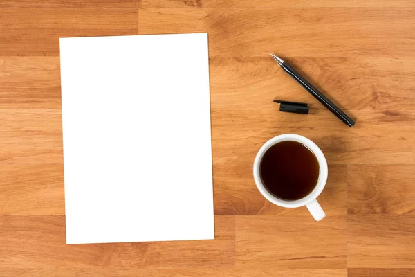Tomt papper är på toppen av träbord med penna och kopp kaffe, uppifrån Visa Flat Lay. — Stockfoto