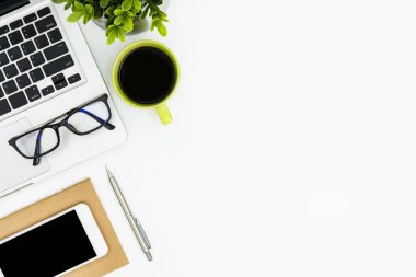 Laptop, kahve ve malzemelerle dolu beyaz ofis masası. Kopyalama alanı olan üst görünüm, düz yatay.