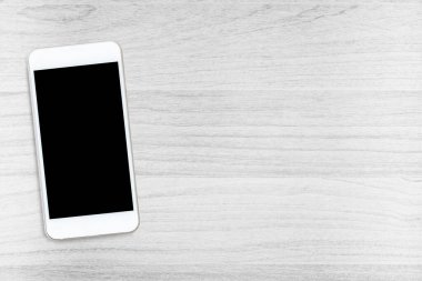 Ahşap masadaki ekranlı beyaz akıllı telefon. Kopyalama alanı olan üst görünüm, düz yatay.
