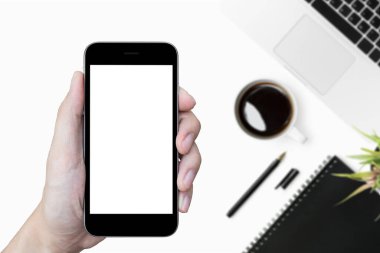 Beyaz ofis masasının üzerinde boş maket ekranı olan akıllı telefonu tutan adam..