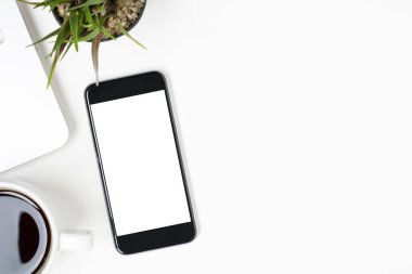 Beyaz ekranlı akıllı telefon beyaz masanın üstündedir. Kopyalama alanı olan üst görünüm, düz yatay.