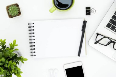 Boş defter sayfası ve malzemeleri olan beyaz ofis masası. Üst manzara, düz uzanma.