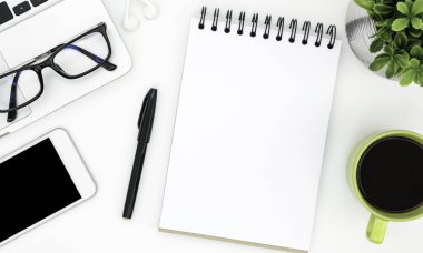 Beyaz ofis masasının ortasında boş bir defter sayfası. Üst manzara, düz uzanma.