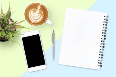Boş defter ve boş ekranlı akıllı telefon Pastel ofis masasının üstünde. Üst manzara, düz uzanma.