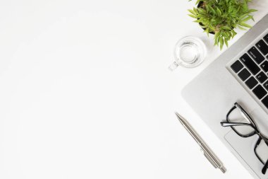 Laptop ve malzemelerle dolu beyaz ofis masası. Kopyalama alanı olan üst görünüm, düz yatay.