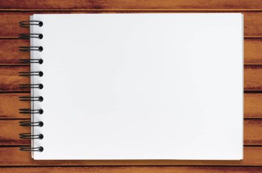 Ahşap ofis masasının üstündeki boş defter sayfası. Üst manzara, düz uzanma.