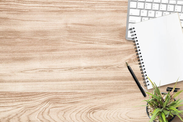 Wood desk table with blank notebook and supplies. Top view with copy space, flat lay.