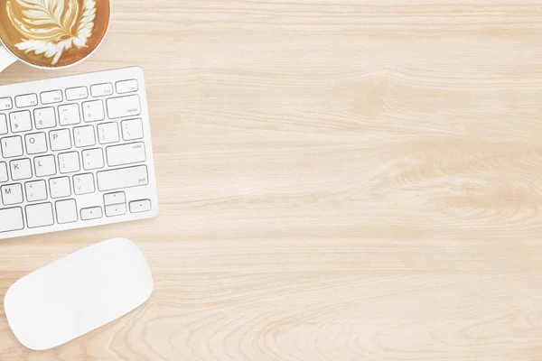 Minimal wood office desk table with computer mouse, keyboard and cup of coffee. Top view with copy space, flat lay.