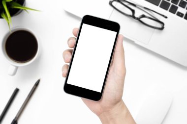 Beyaz ofis masasının üzerinde beyaz ekranlı ve malzemeli akıllı telefon..