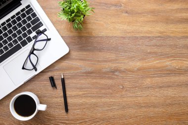 Laptoplu ahşap ofis masası, bir fincan kahve ve malzeme. Kopyalama alanı olan üst görünüm, düz yatay.