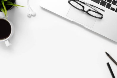 Laptop bilgisayarı, kahve ve ofis malzemeleri olan beyaz ofis masası. Kopyalama alanı olan üst görünüm, düz yatay.