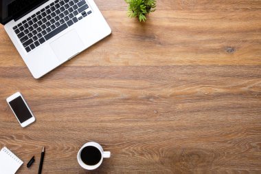 Laptop bilgisayarlı ahşap masa masası, akıllı telefon, bir fincan kahve ve malzeme. Kopyalama alanı olan üst görünüm, düz yatay.