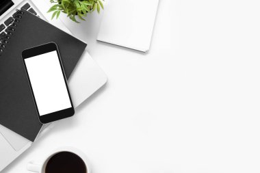 Beyaz ofis masası, akıllı telefon, boş ekran ve diğer ofis malzemeleri. Kopyalama alanı olan üst görünüm, düz yatay.