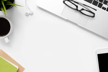Laptop bilgisayarı, kahve ve diğer ofis malzemeleriyle dolu beyaz ofis masası. Kopyalama alanı olan üst görünüm, düz yatay.