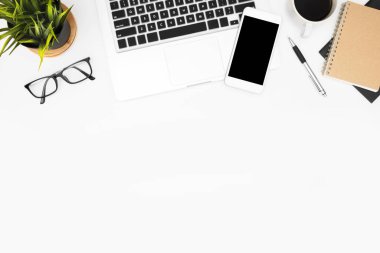 Laptop, akıllı telefon ve ofis malzemeleriyle dolu beyaz ofis masası. Kopyalama alanı olan üst görünüm, düz yatay.