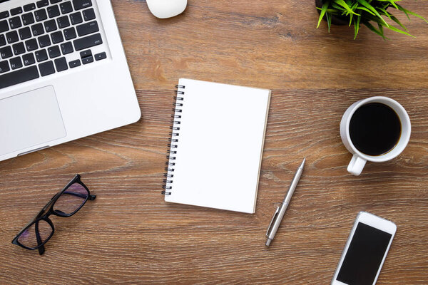 Деревянный стол с чистым блокнотом, компьютерными гаджетами и принадлежностями. Вид сверху, плоский
.