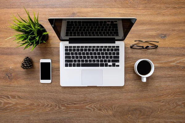 Laptop bilgisayar ve ofis malzemeleriyle dolu ahşap ofis masası. Kopyalama alanı olan üst görünüm, düz yatay.