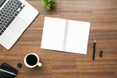 Kalemli boş defter ahşap ofis masasının üstünde. Üst manzara, düz uzanma.