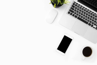 Laptop bilgisayarlı beyaz ofis masası, boş ekranlı akıllı telefon ve malzemeler. Kopyalama alanı olan üst görünüm, düz yatay.
