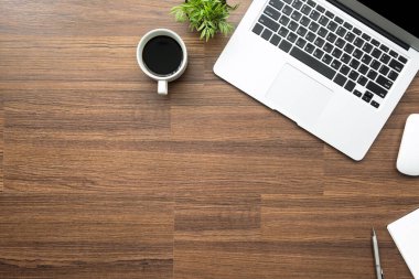 Diz üstü bilgisayarı, akıllı telefonu ve malzemeleri olan ahşap ofis masası. Kopyalama alanı olan üst görünüm, düz yatay.