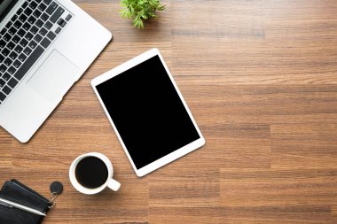 Tablet ve malzemelerle ahşap ofis masası. Kopyalama alanı olan üst görünüm, düz yatay.