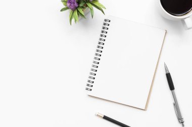 Boş sayfası olan defter beyaz ofis masasının üzerinde. 