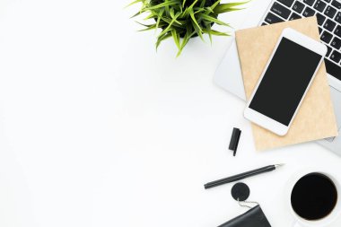 Akıllı telefon, dizüstü bilgisayar ve malzemelerle dolu beyaz ofis masası. Kopyalama alanı olan üst görünüm, düz yatay.