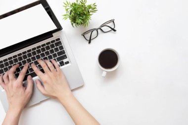 Laptop bilgisayarında beyaz ofis masasının üzerinde beyaz beyaz ekranlı bir kahve bardağıyla yazı yazan bir adam. Kopyalama alanı olan üst görünüm, düz yatay.