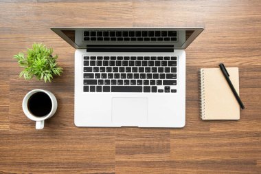 Laptop bilgisayarlı ahşap ofis masası, bir fincan kahve ve ofis malzemeleri. Üst görünüm, düz görünüm.