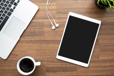 Boş ekranlı tablet ahşap ofis masasının üstünde bilgisayar ve kahveyle birlikte. Üst manzara, düz uzanma.