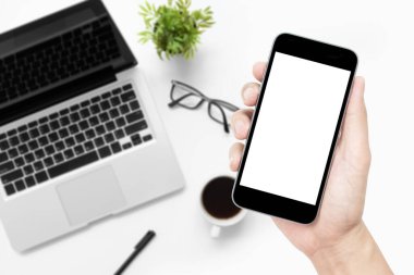 Beyaz ofis masasının üzerinde beyaz ekranlı ve malzemeli akıllı telefon..