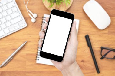El, ahşap ofis masasının üzerinde telefon tutuyor.