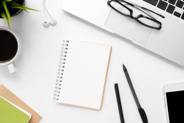 Boş defterli beyaz ofis masası ve diğer ofis yemekleri.
