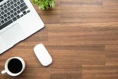 Dizüstü bilgisayarlı ahşap ofis masası, bir fincan kahve ve malzeme. Kopyalama alanı olan üst görünüm, düz yatay.