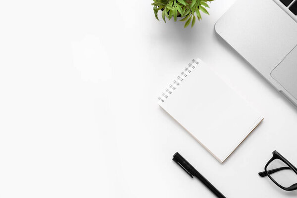 Белый стол с чистым блокнотом, ноутбуком и другими офисными принадлежностями. Вид сверху с копировальным пространством, плоская кладка.