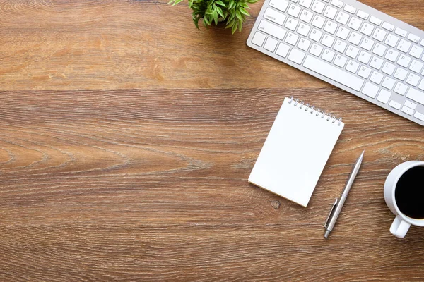 Wood office desk table with blank notebook and supplies. Top vie