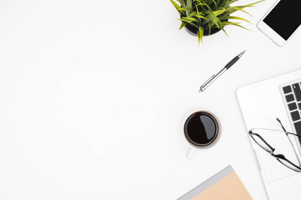 Стол белого стола с ноутбуком, чашкой кофе и принадлежностями.
