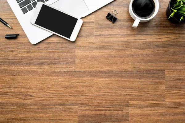 Wood office desk table with laptop, smartphone, cup of coffee and office supplies. Top view with copy space, flat lay.