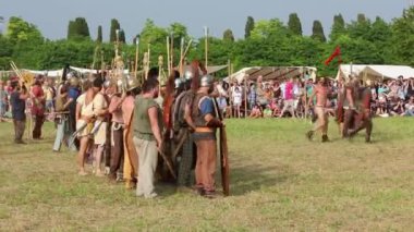 AQUILEIA, İtalya - 22 Haziran 2014: Yıllık Antik Roma canlandırmasında Romalılar ve Carnic Keltler arasındaki çatışmada Kelt askerleri, Carnic komutanının esir alınmış Roma amblemlerini göstermesi ve askerlerini savaşa teşvik etmesiyle,