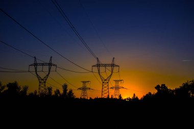 Gün batımında yüksek voltajlı elektrik hatları. Elektrik dağıtım istasyonu .