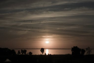 nehir ve güç hatları unsurları ile gün batımında güneş