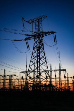 Gün batımında yüksek voltajlı elektrik hatları. Elektrik dağıtım istasyonu .