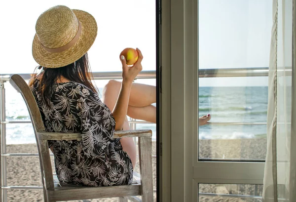 A girl with an apple looking to the sea