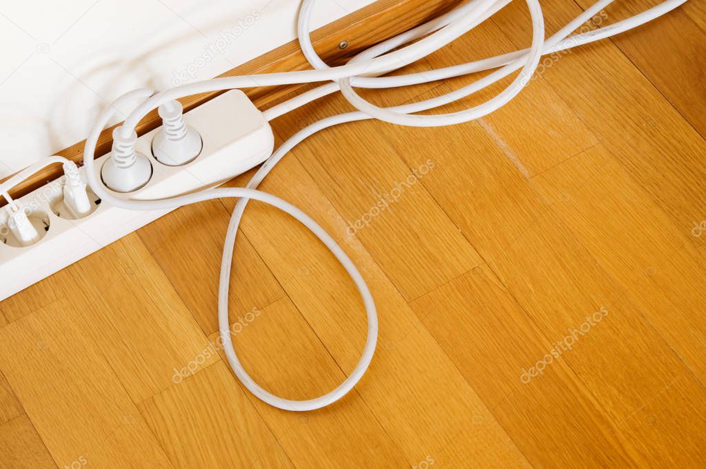 Multiple socket and plugs on wooden floor.